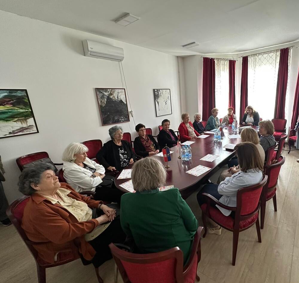 Participants from the workshop, sitting in the room, discussing the completed workshops. Certificates visible on the table.  