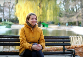 Maja, a graduate student at the Academy of Arts in Novi Sad, Serbia, sitting on a bench in a park.